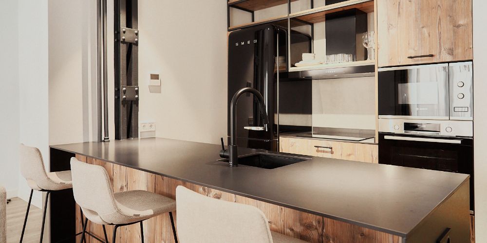 Cocina de diseño moderno con isla y detalles industriales, una muestra del estilo de vida Signature Living de neodomos.